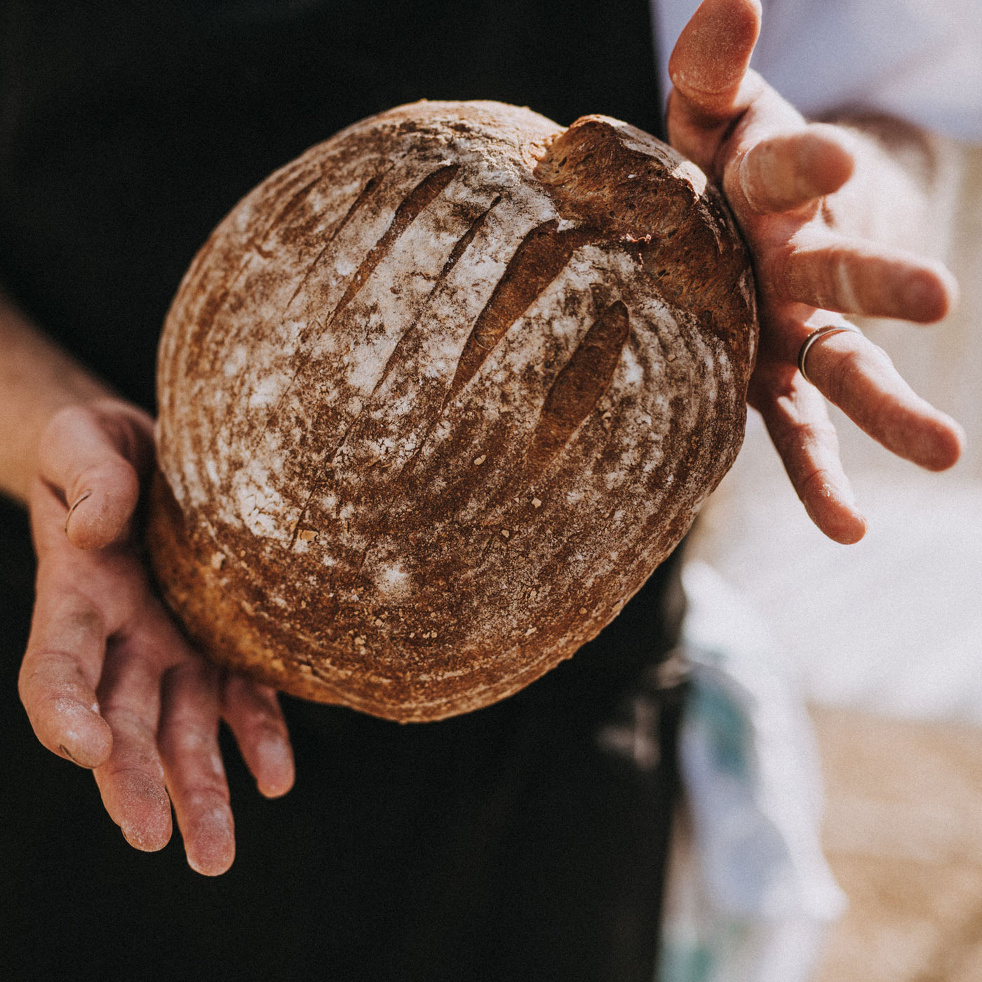 Close up of a man holding sourdough bread.